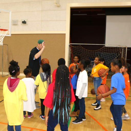 A group of children are playing basketball in a gym
