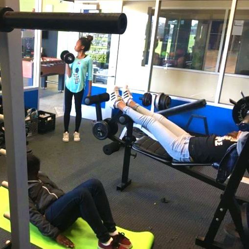 A woman is lifting a dumbbell in a gym
