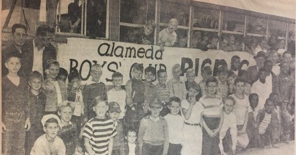 A group of people standing in front of a sign that says alameda boys camp picnic