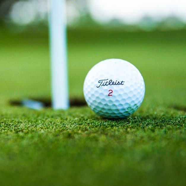 A golf ball is sitting on top of a green next to a hole.