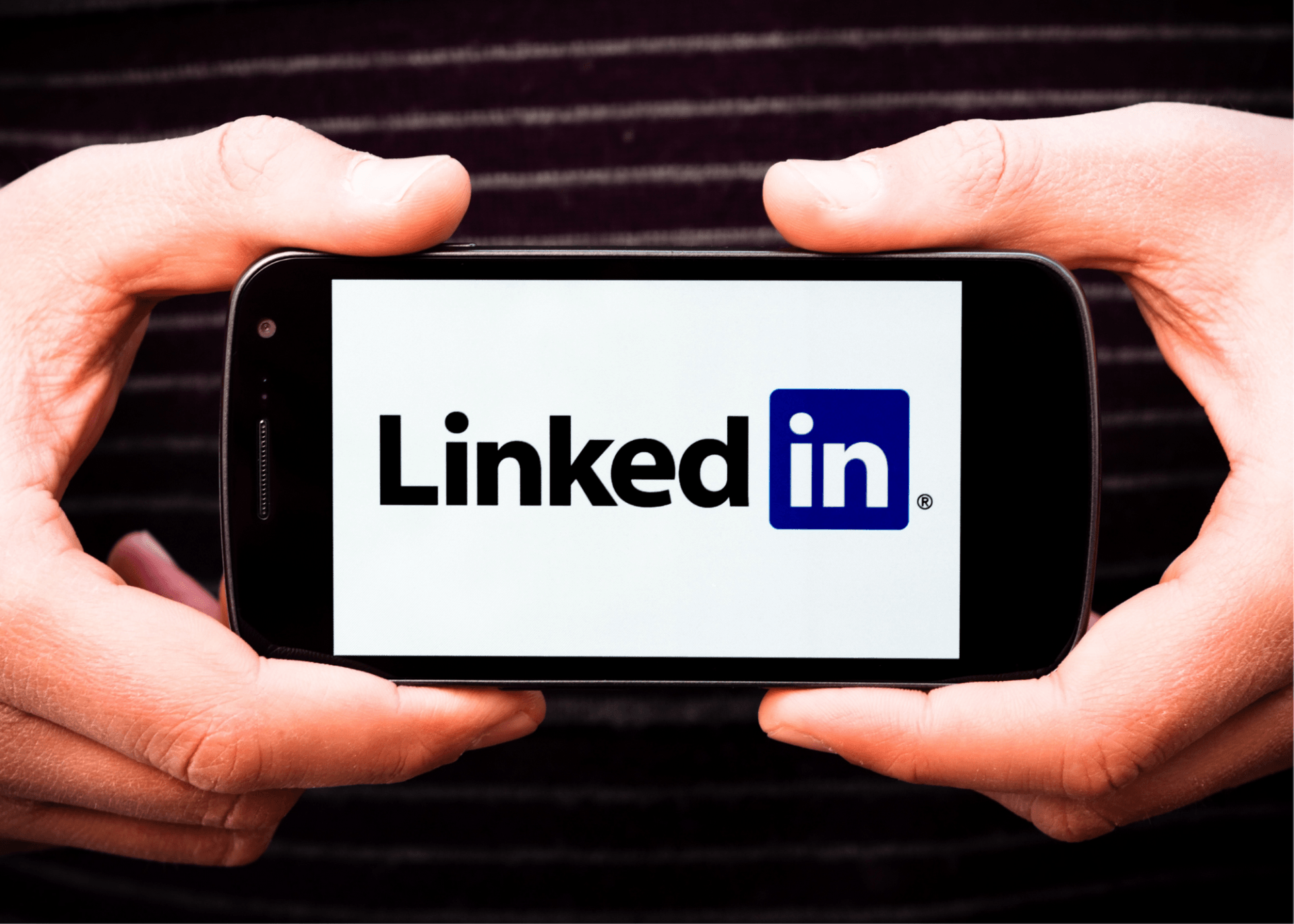 A person is holding a cell phone with the linkedin logo on it.