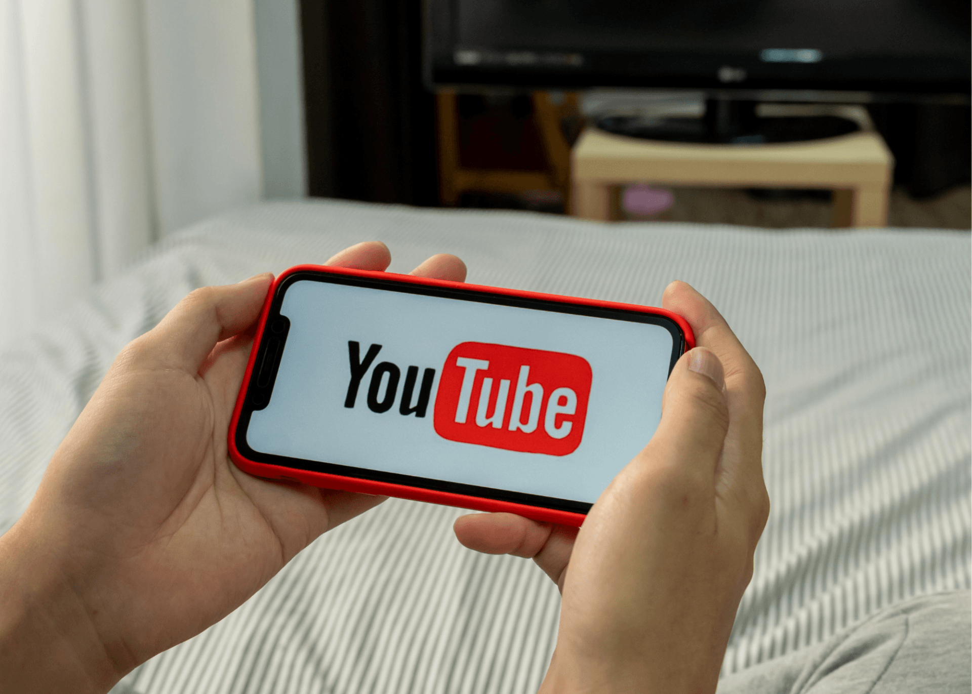 A person is holding a cell phone with the youtube logo on it.