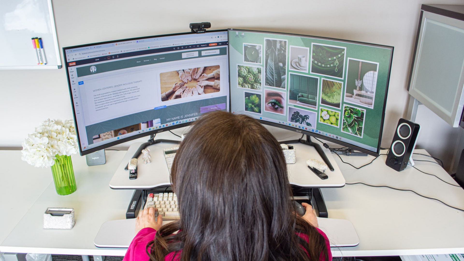 Person working at dual monitors in a bright office, viewing a webpage and image grid.
