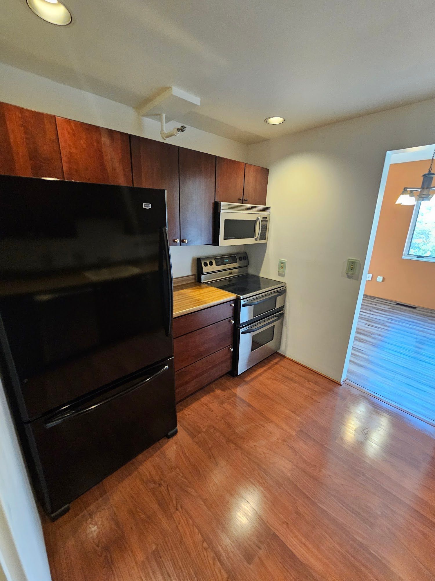 A kitchen with a black refrigerator , stove , microwave and wooden cabinets.