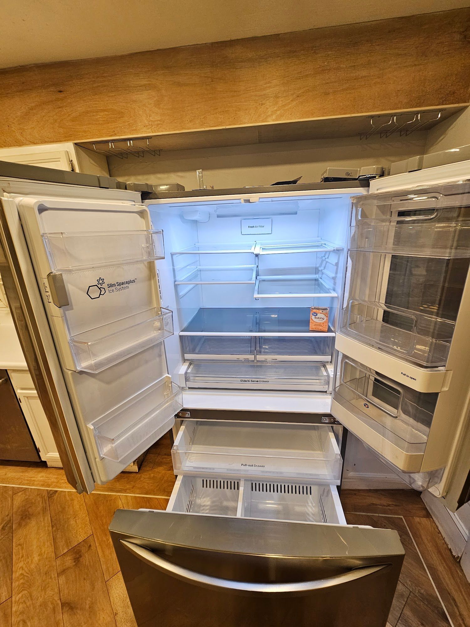 An empty refrigerator with the door open in a kitchen.