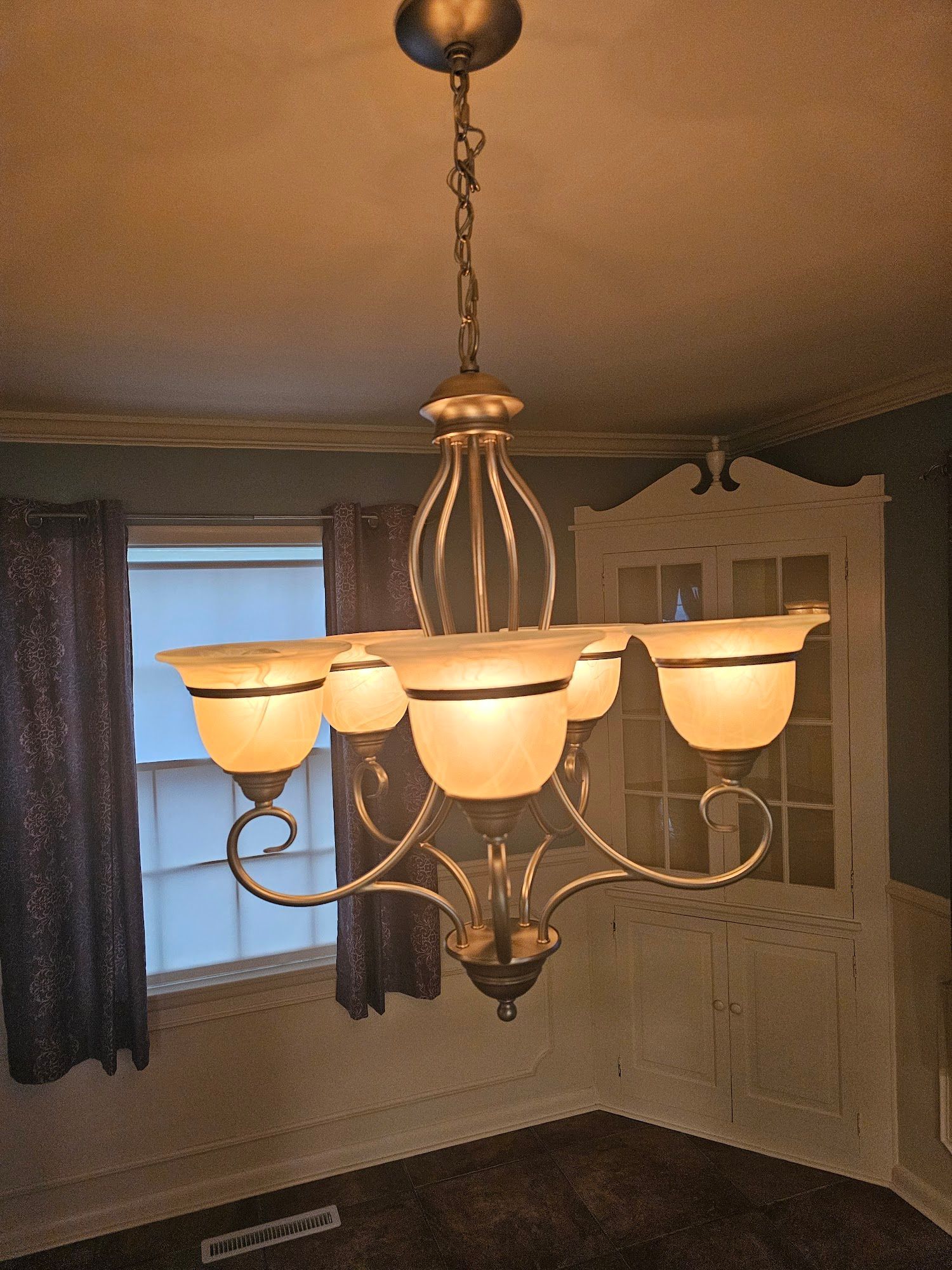 A dining room with a chandelier hanging from the ceiling