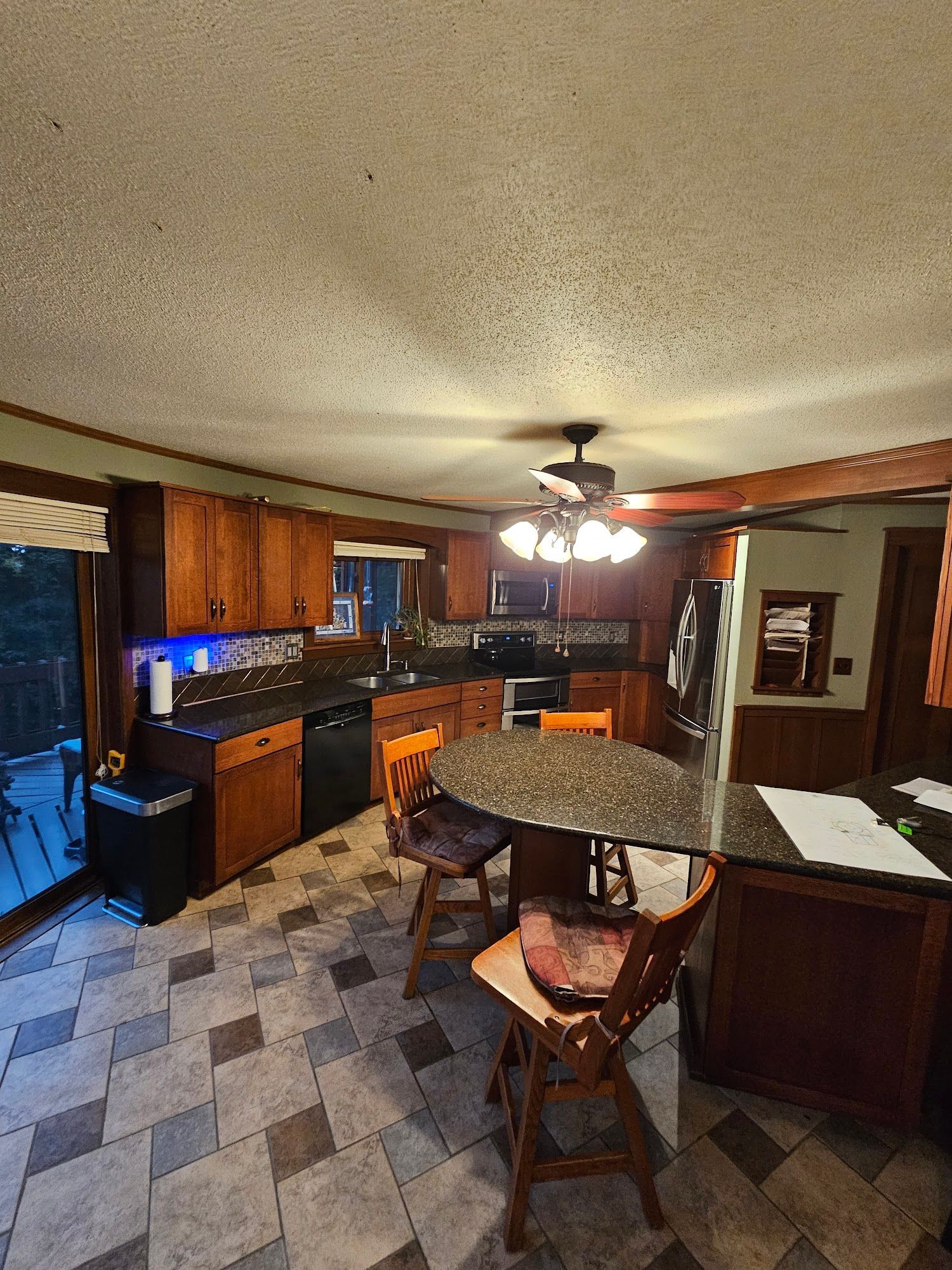 A kitchen with a table and chairs and a ceiling fan.