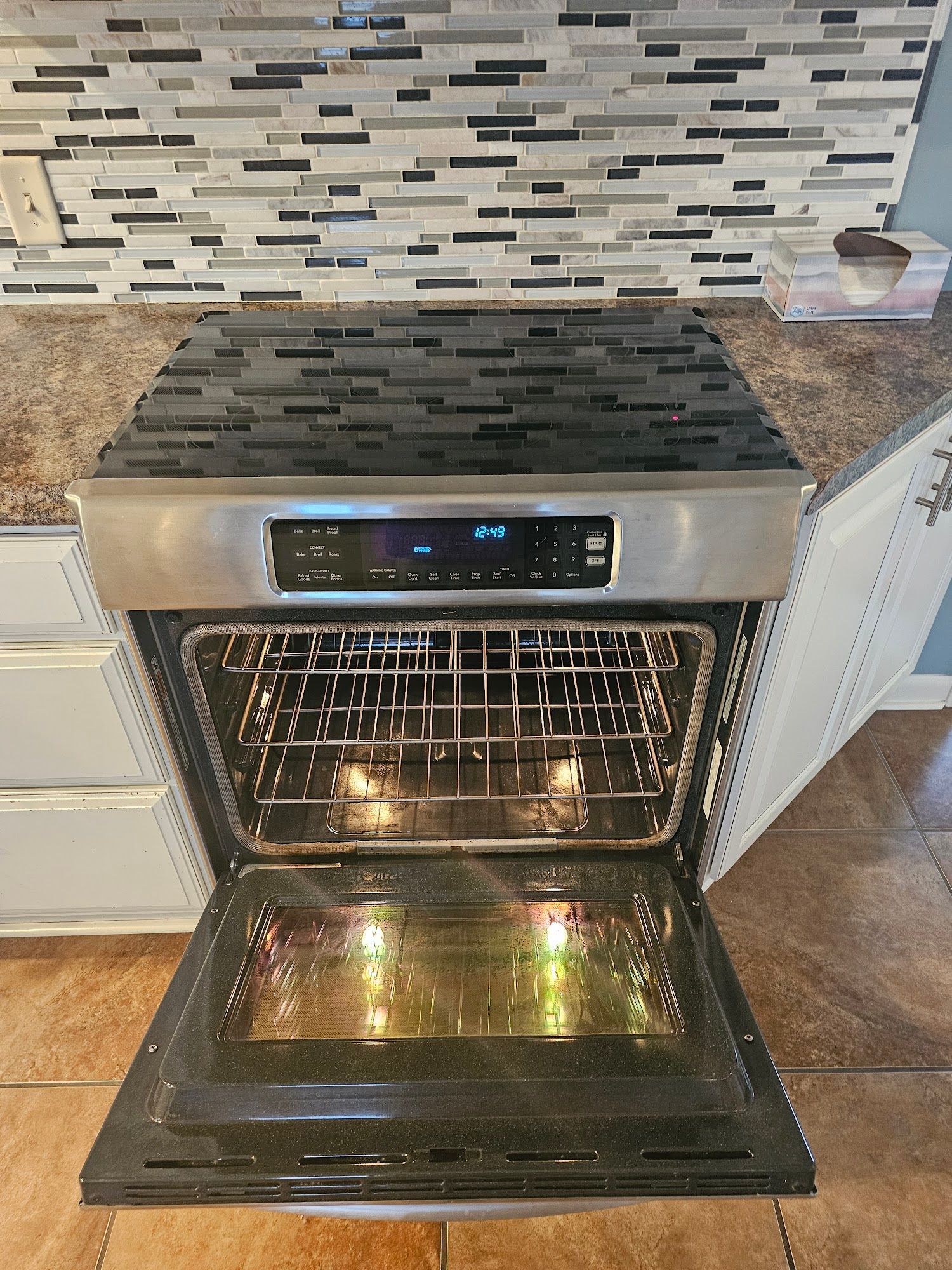 A stainless steel oven with the door open in a kitchen.