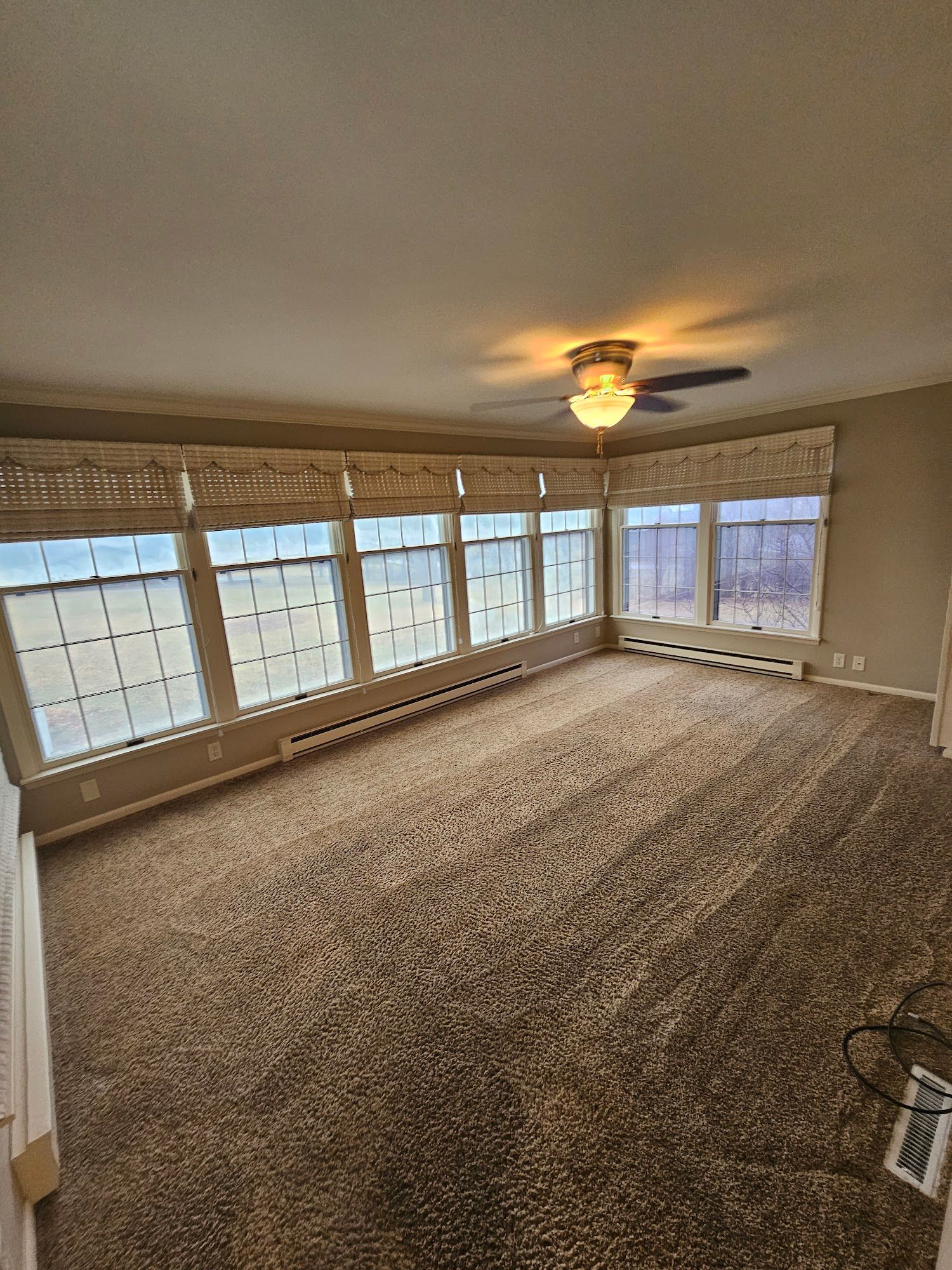 A living room with a lot of windows and a ceiling fan.