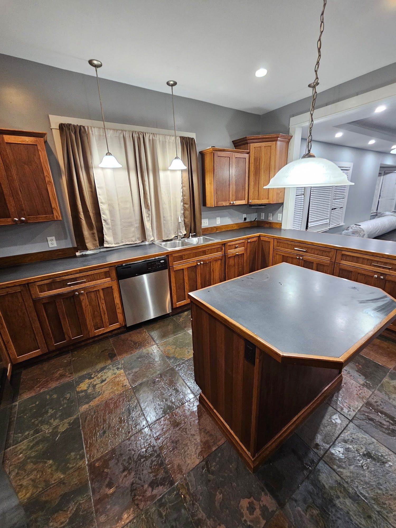 A kitchen with wooden cabinets , stainless steel appliances , and a large island.