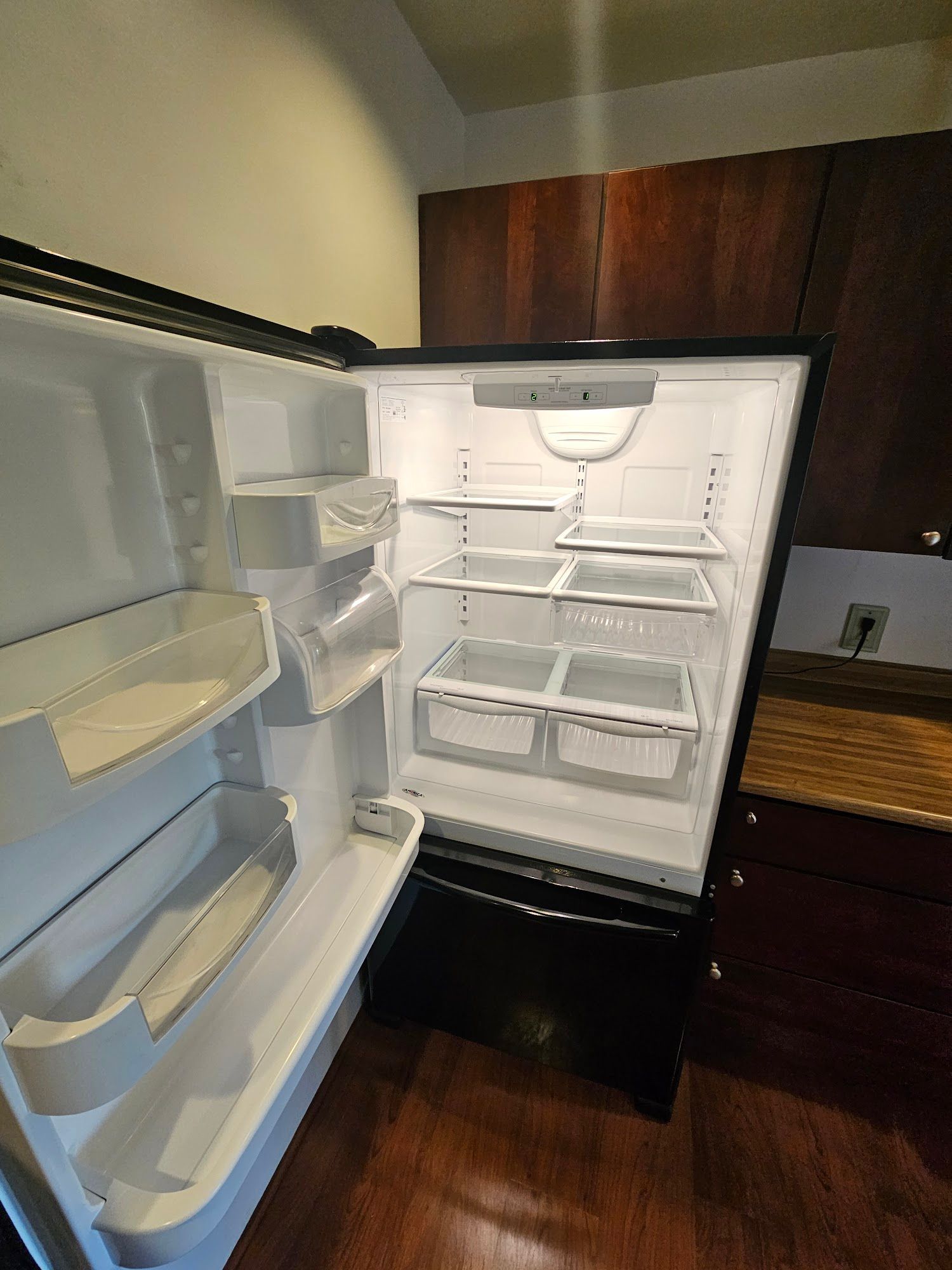 An empty refrigerator in a kitchen with the door open.