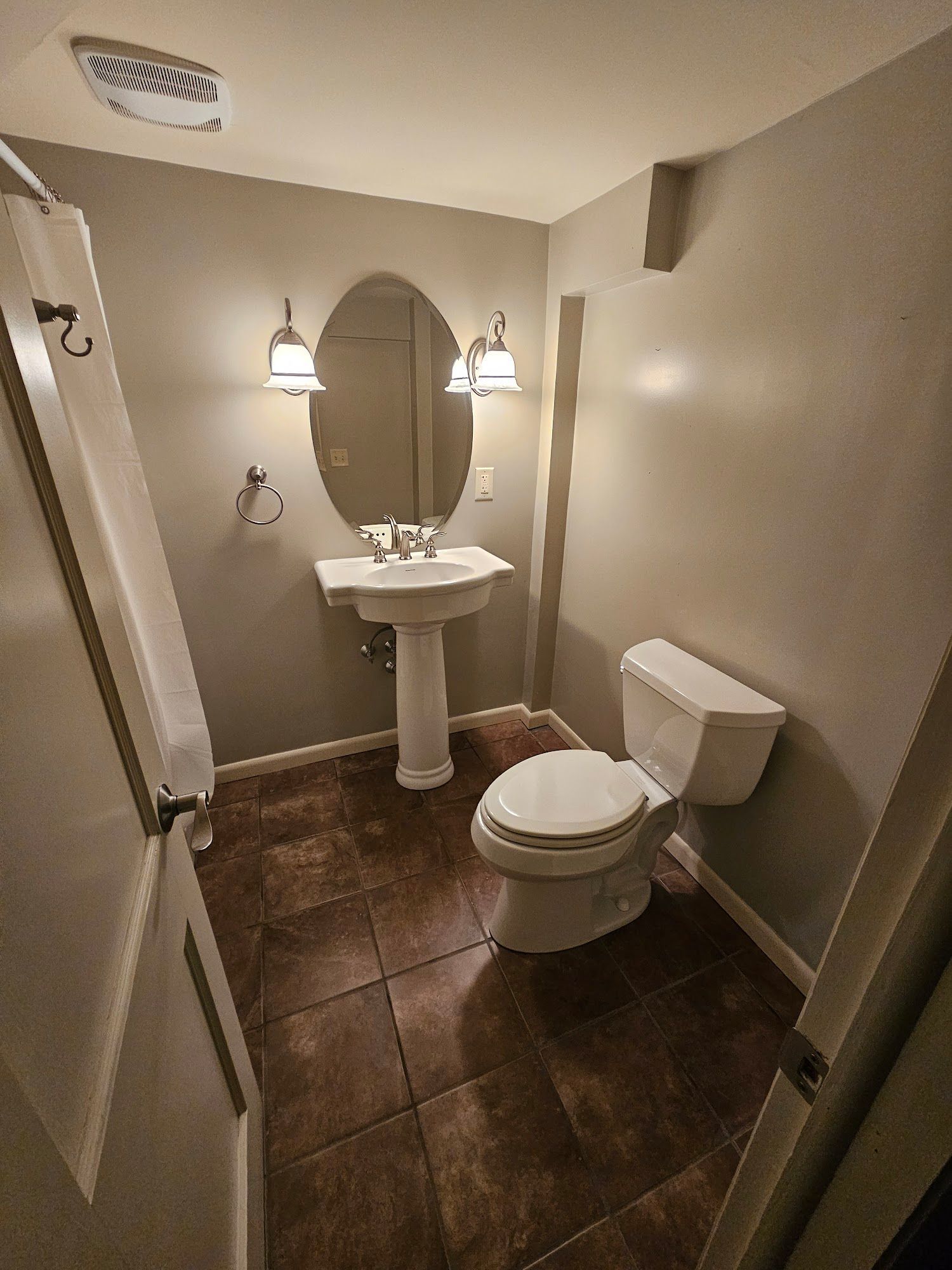 A bathroom with a toilet , sink and mirror.