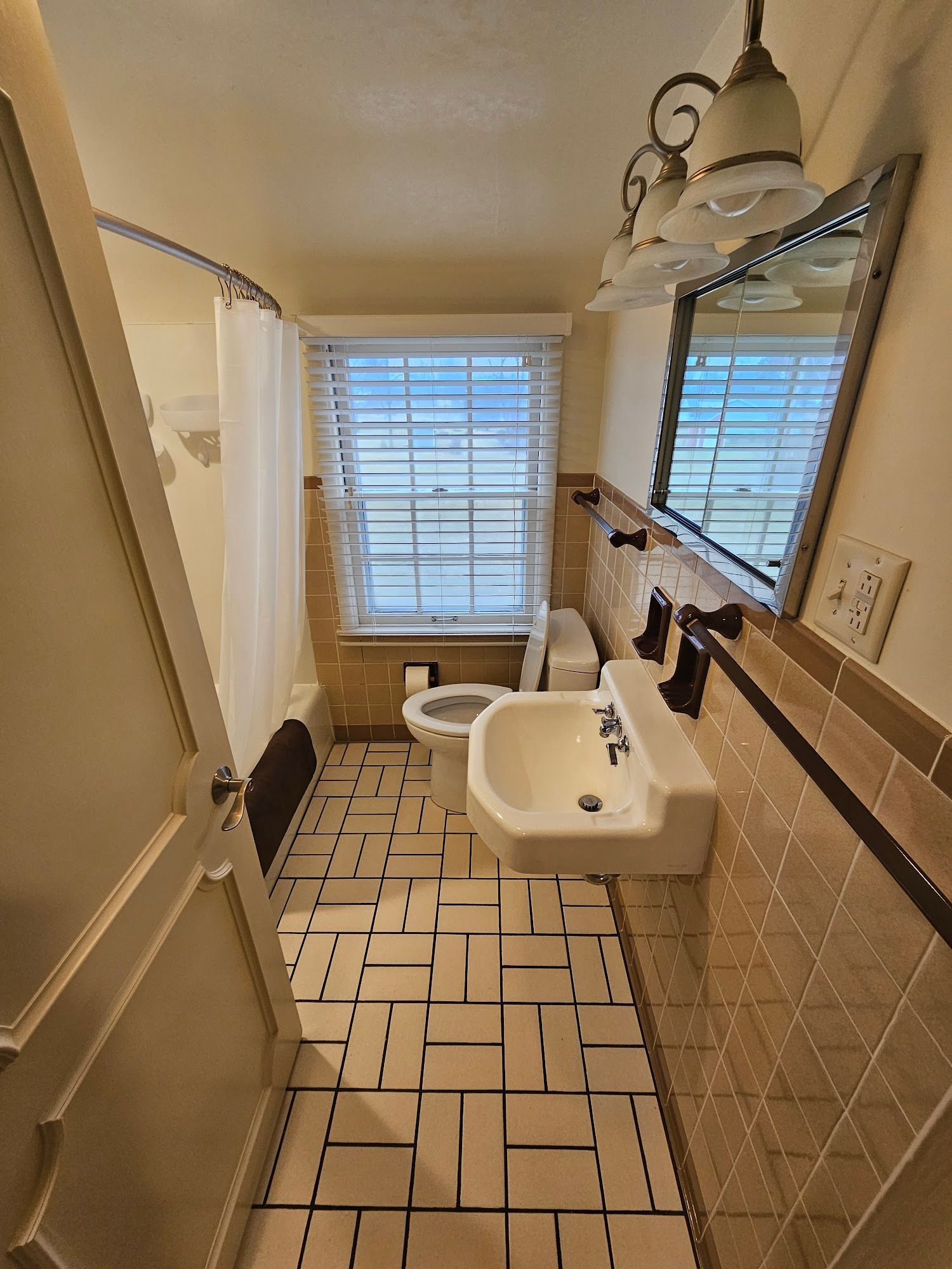A bathroom with a sink , toilet , mirror and window.
