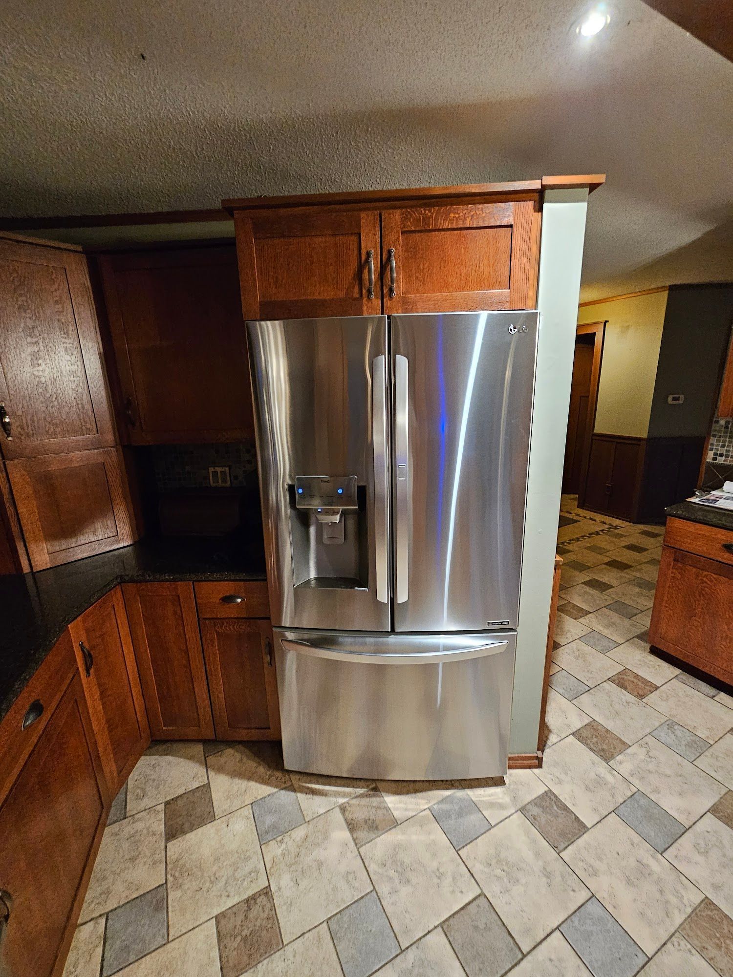 A stainless steel refrigerator with a water dispenser is in a kitchen.