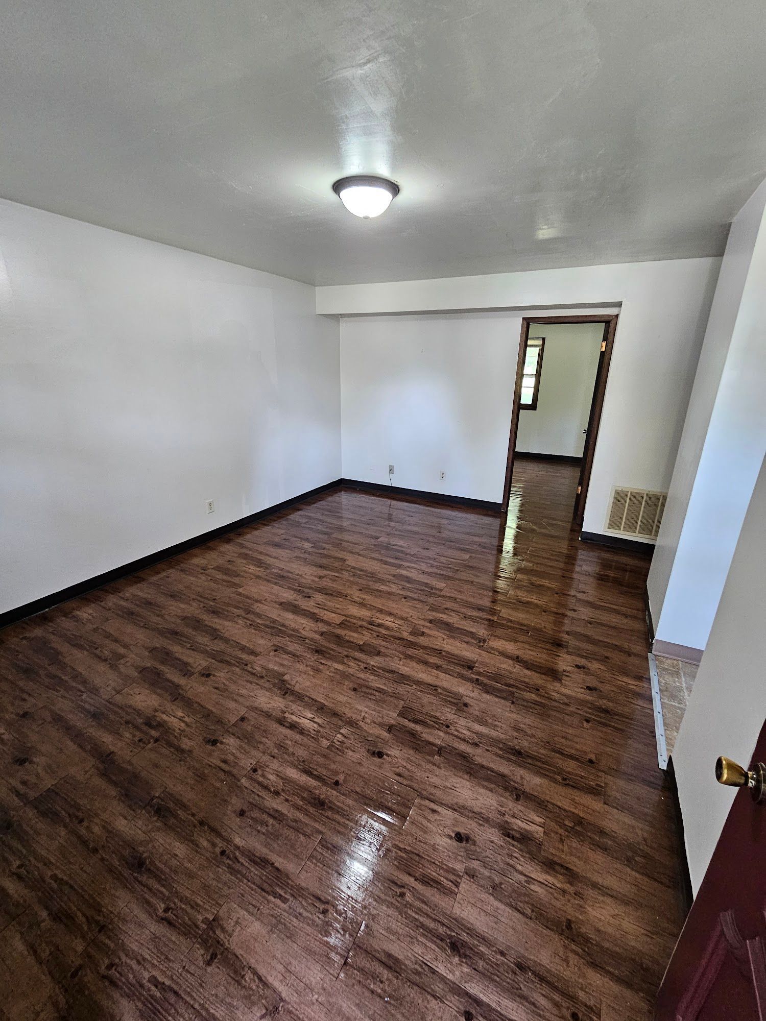 An empty living room with hardwood floors and white walls.