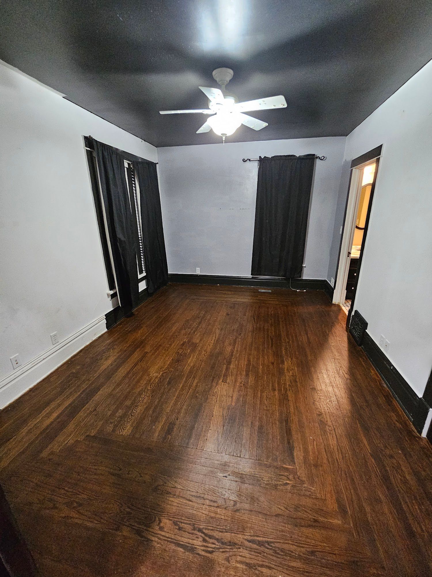 A living room with hardwood floors and a ceiling fan.