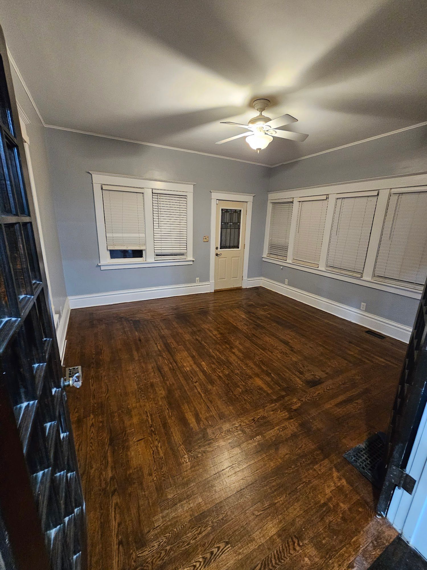 An empty living room with hardwood floors and a ceiling fan.