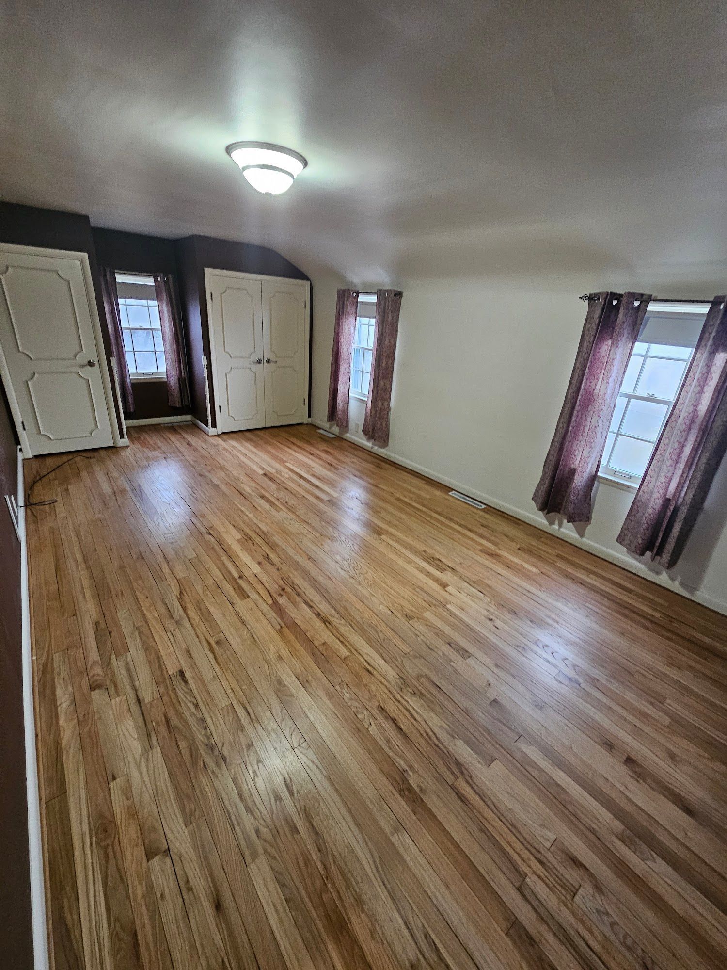 A large empty room with hardwood floors and windows.
