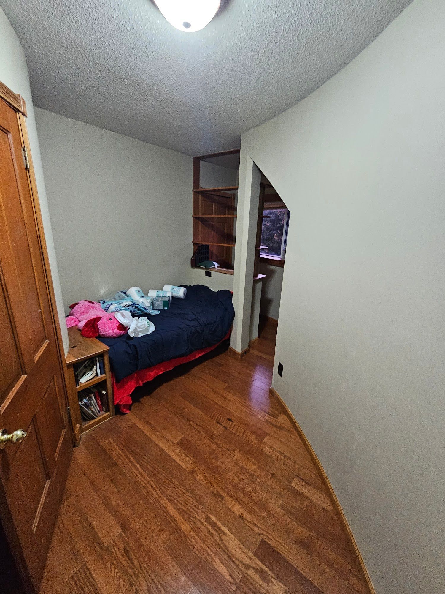 A bedroom with hardwood floors and a bed.