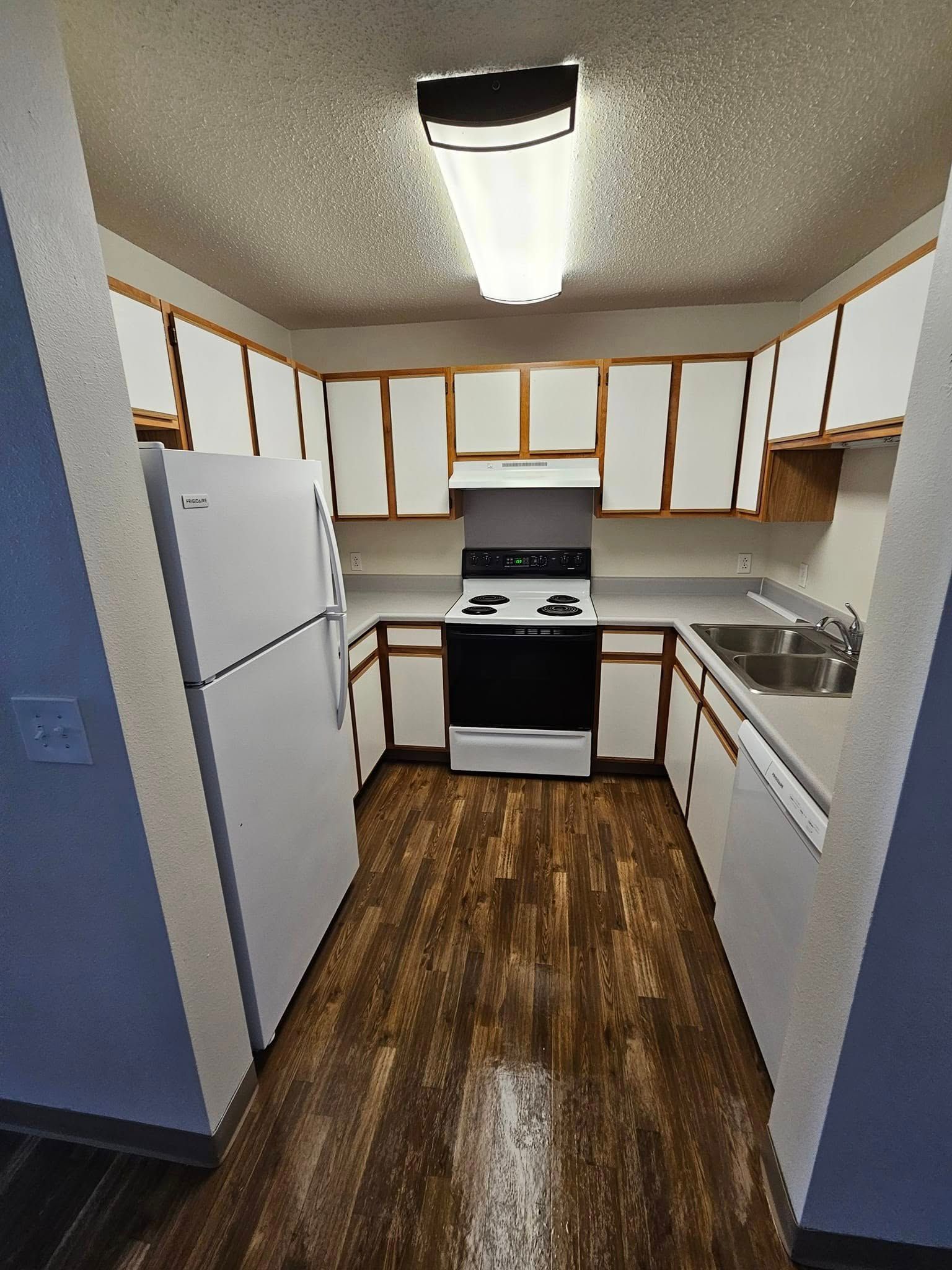 A kitchen with a stove , refrigerator , sink and cabinets.