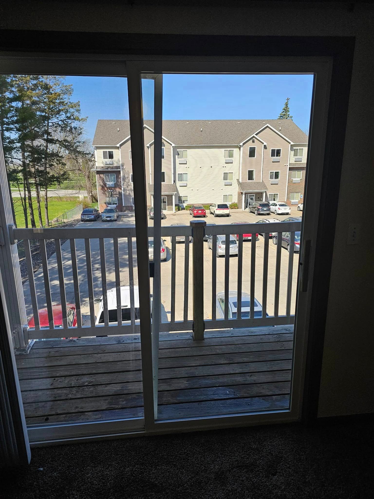 A sliding glass door leading to a balcony with a view of a parking lot.