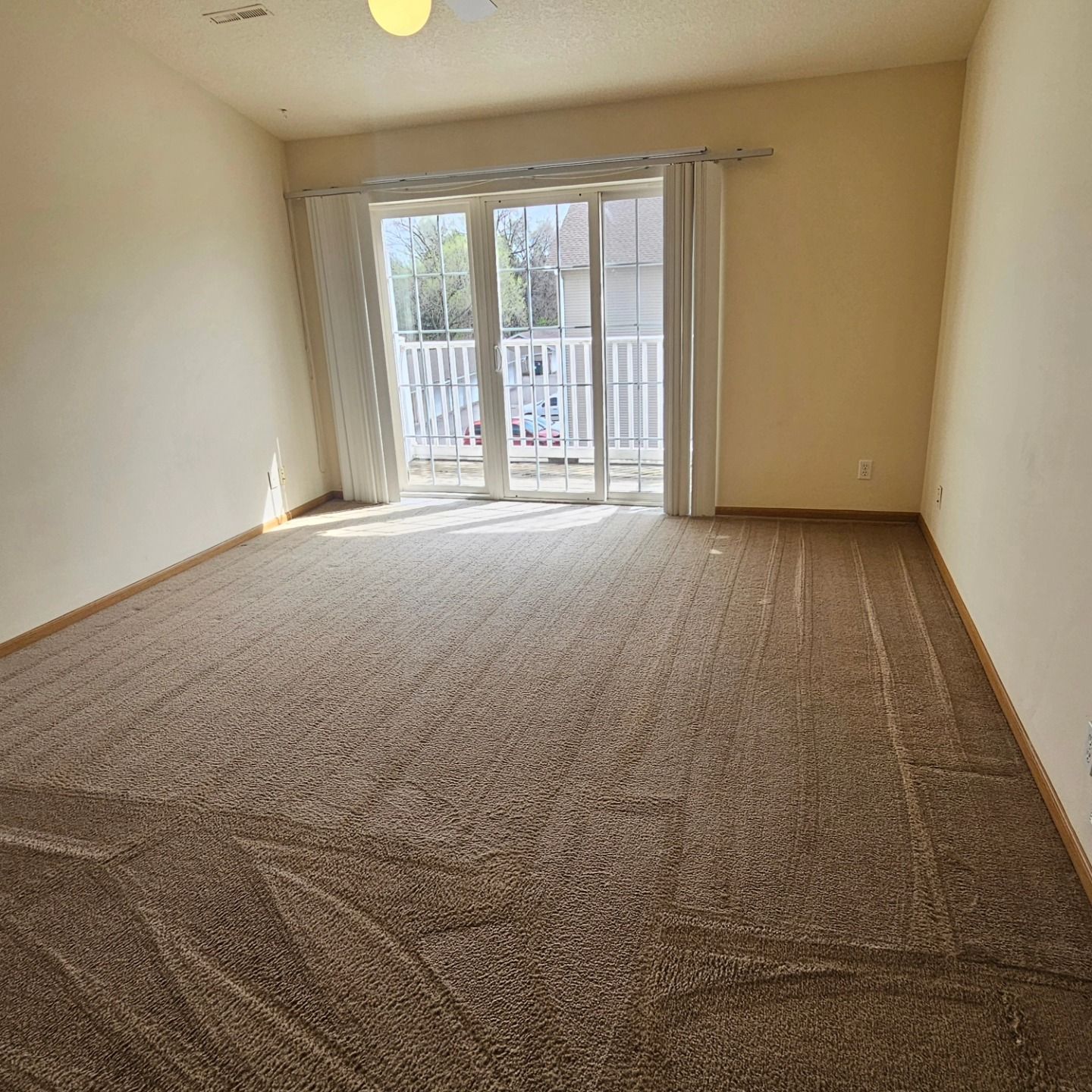 An empty living room with a sliding glass door and a balcony.