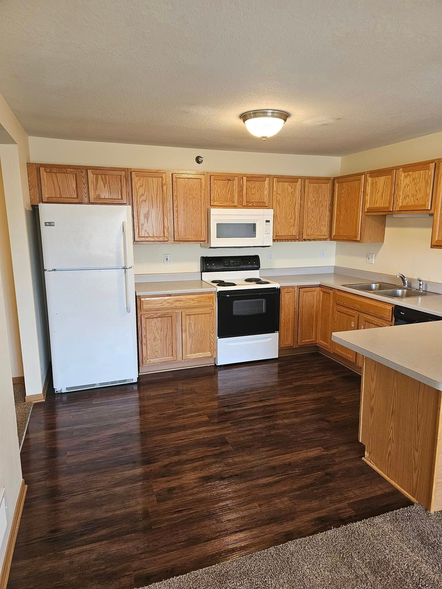 An empty kitchen with wooden cabinets and a white refrigerator