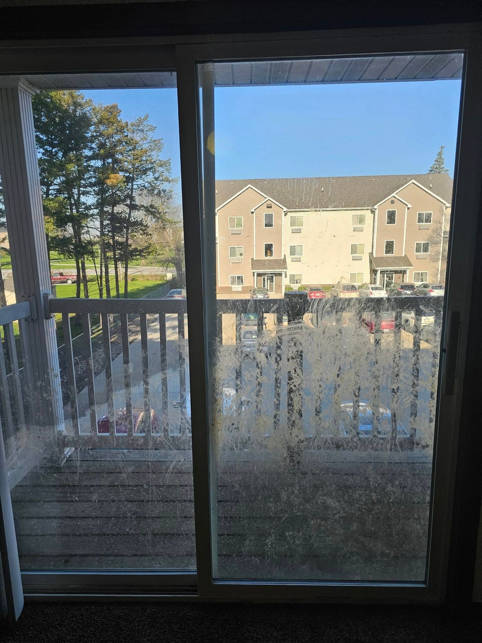 A sliding glass door leading to a balcony with a view of a building.