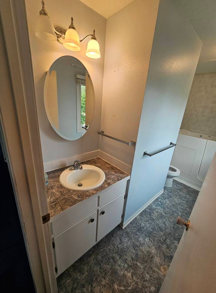 A bathroom with a sink , mirror and toilet.