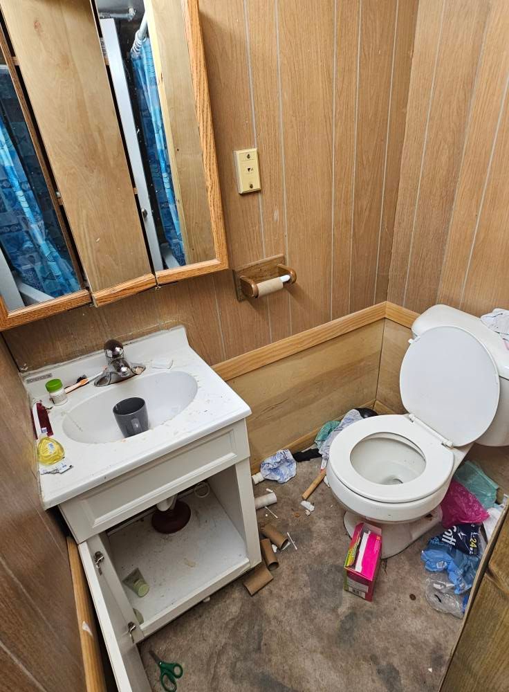 A bathroom with a toilet , sink and mirror.