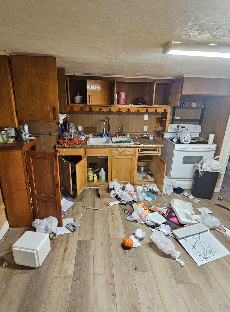 A kitchen with a lot of trash on the floor.