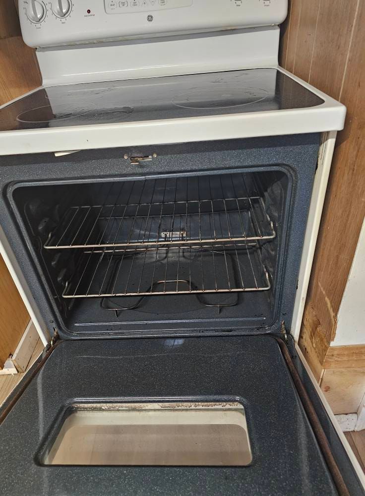 A white stove top oven with the door open in a kitchen.