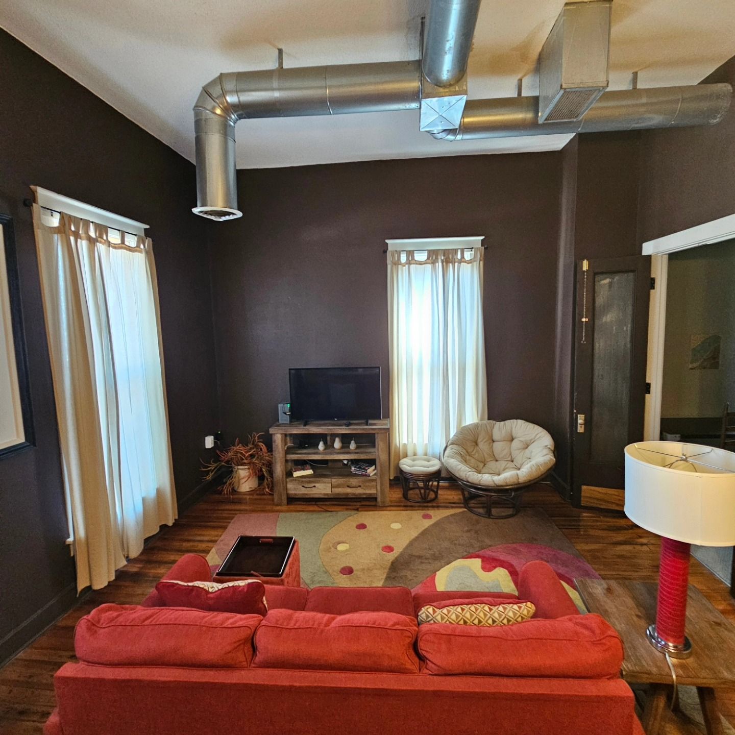 A living room with a red couch and a tv