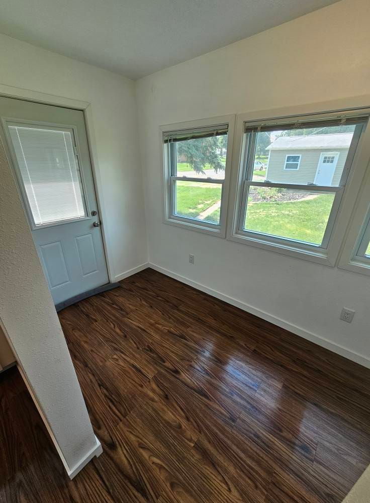 An empty room with hardwood floors and a door.