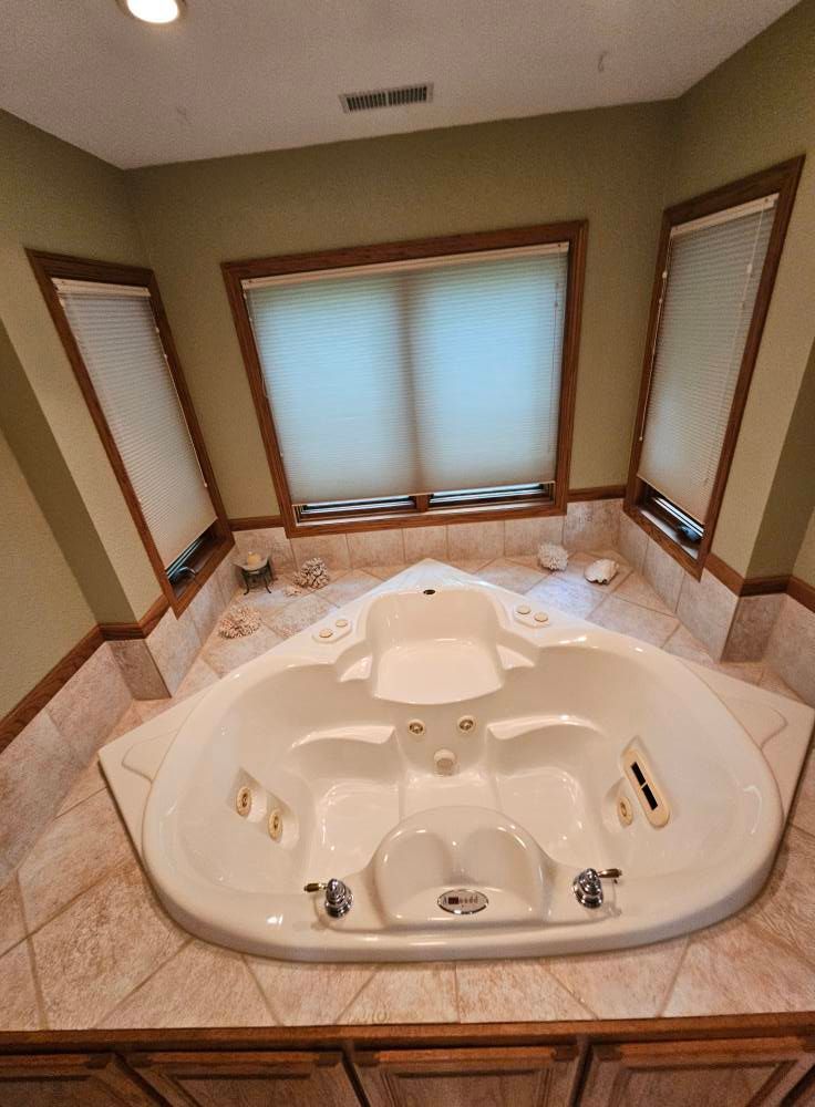 There is a large jacuzzi tub in the middle of the bathroom.