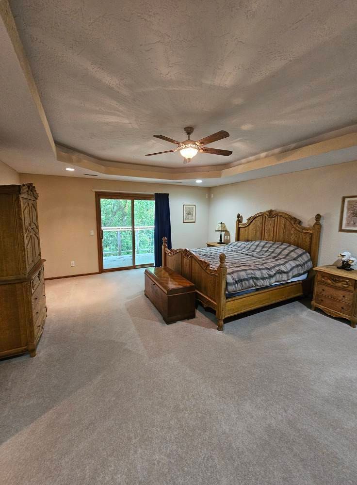 A bedroom with a bed , nightstand , dresser and ceiling fan.