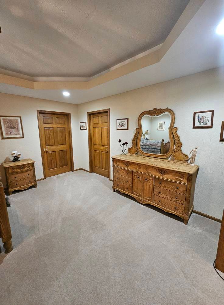 A bedroom with a dresser , nightstand , mirror and bed.