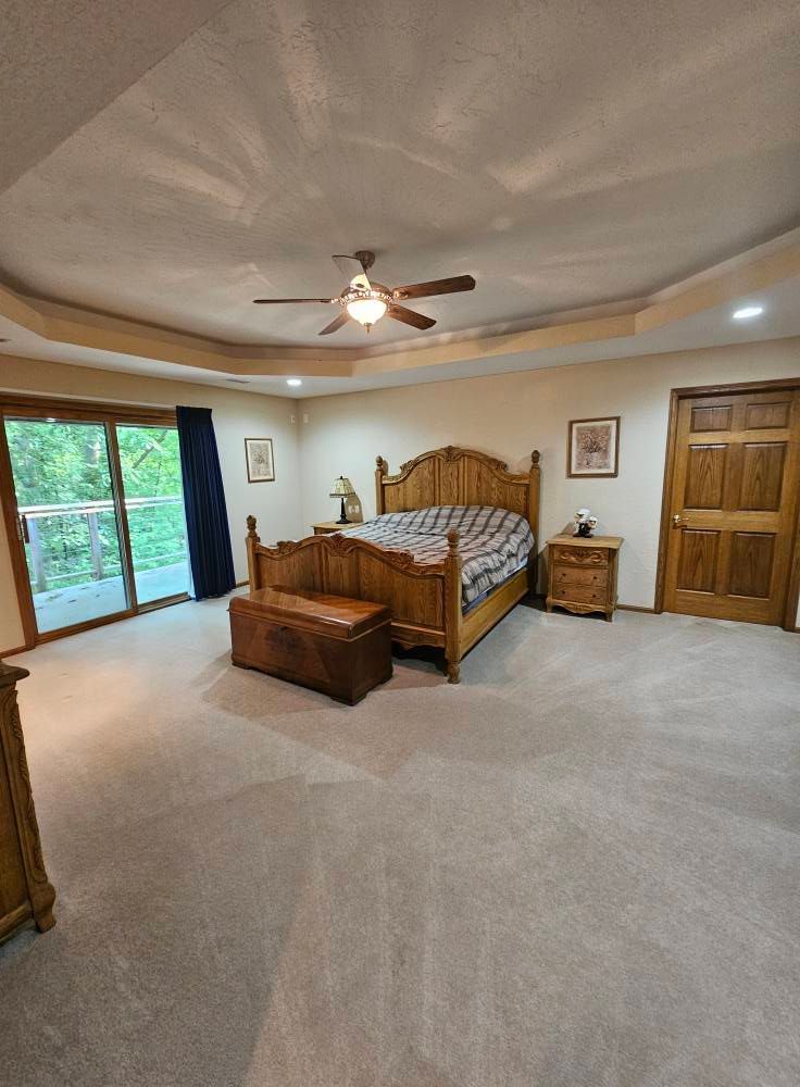 A bedroom with a bed , dresser , nightstand , and ceiling fan.