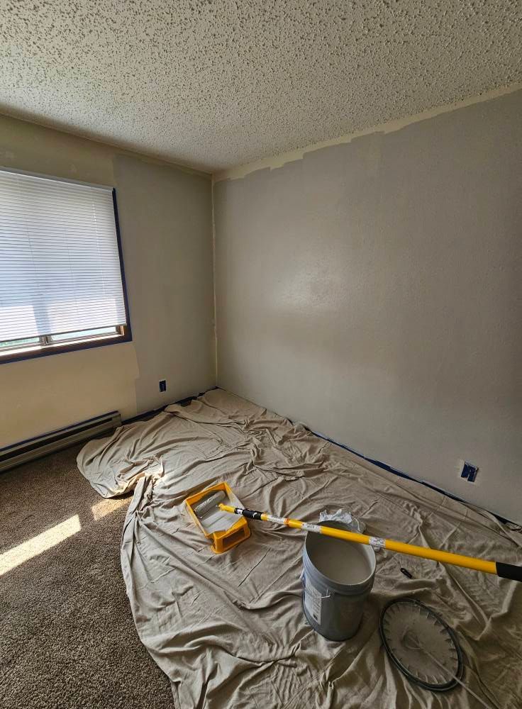 A room is being painted with a bucket of paint and a roller.
