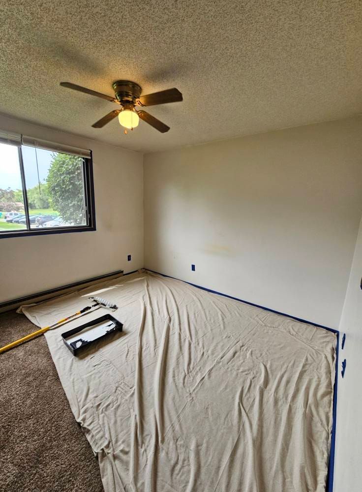 A bedroom with a ceiling fan and a blanket on the floor.