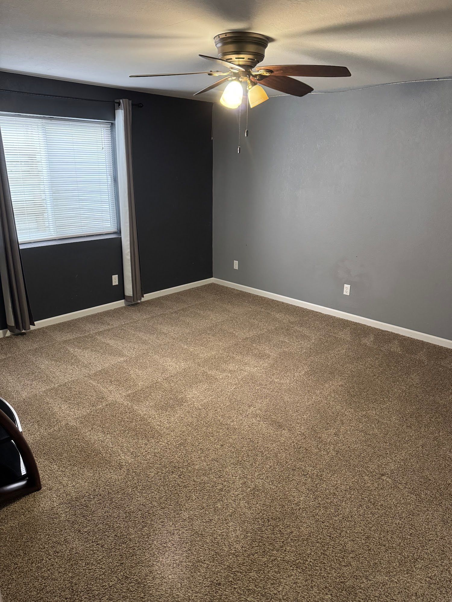 An empty room with a ceiling fan and a window.