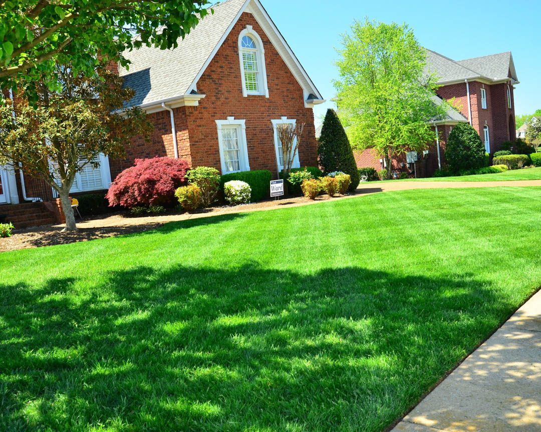 A brick house with a lush green lawn in front of it.