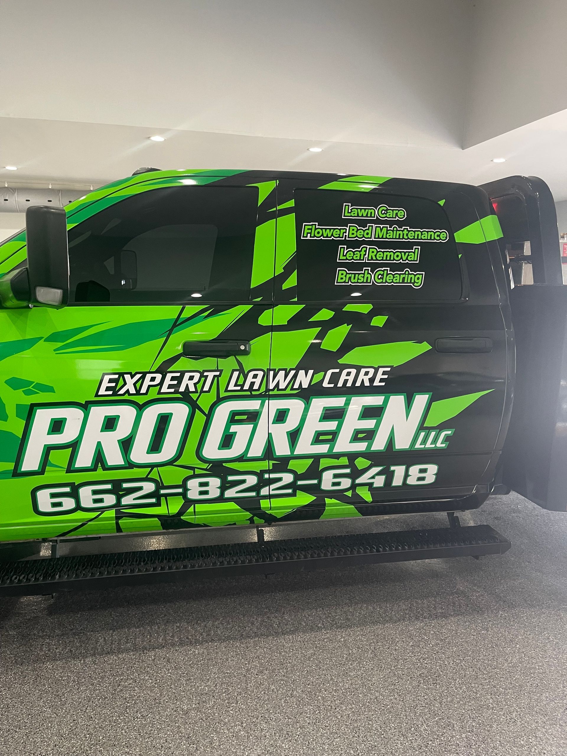 A green and black truck is parked in a garage.