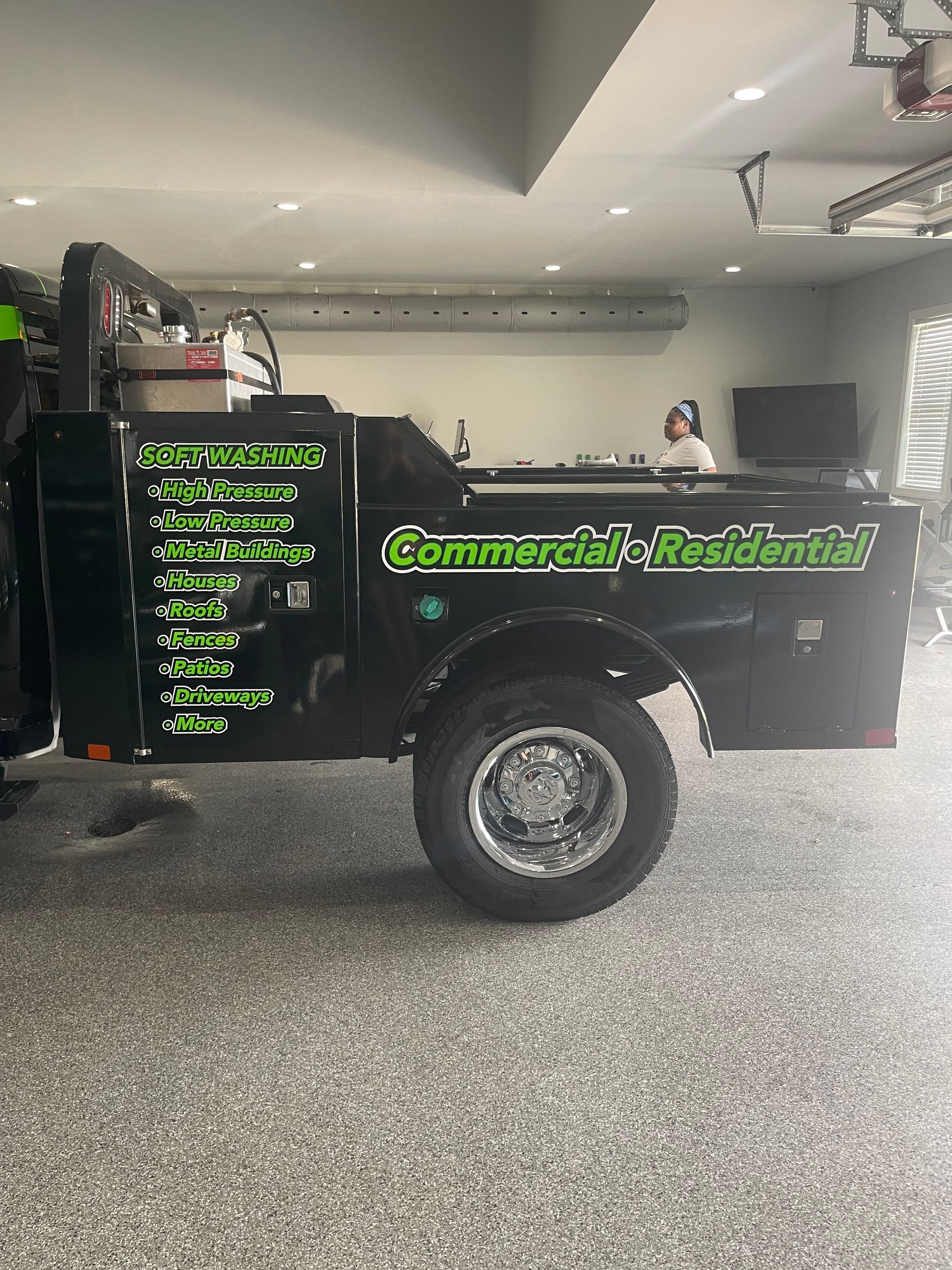 A black truck with a trailer attached to it is parked in a garage.