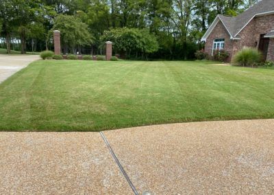 A lush green lawn is in front of a brick house.