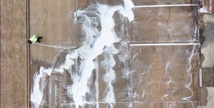 An aerial view of a person cleaning a wall with a hose.