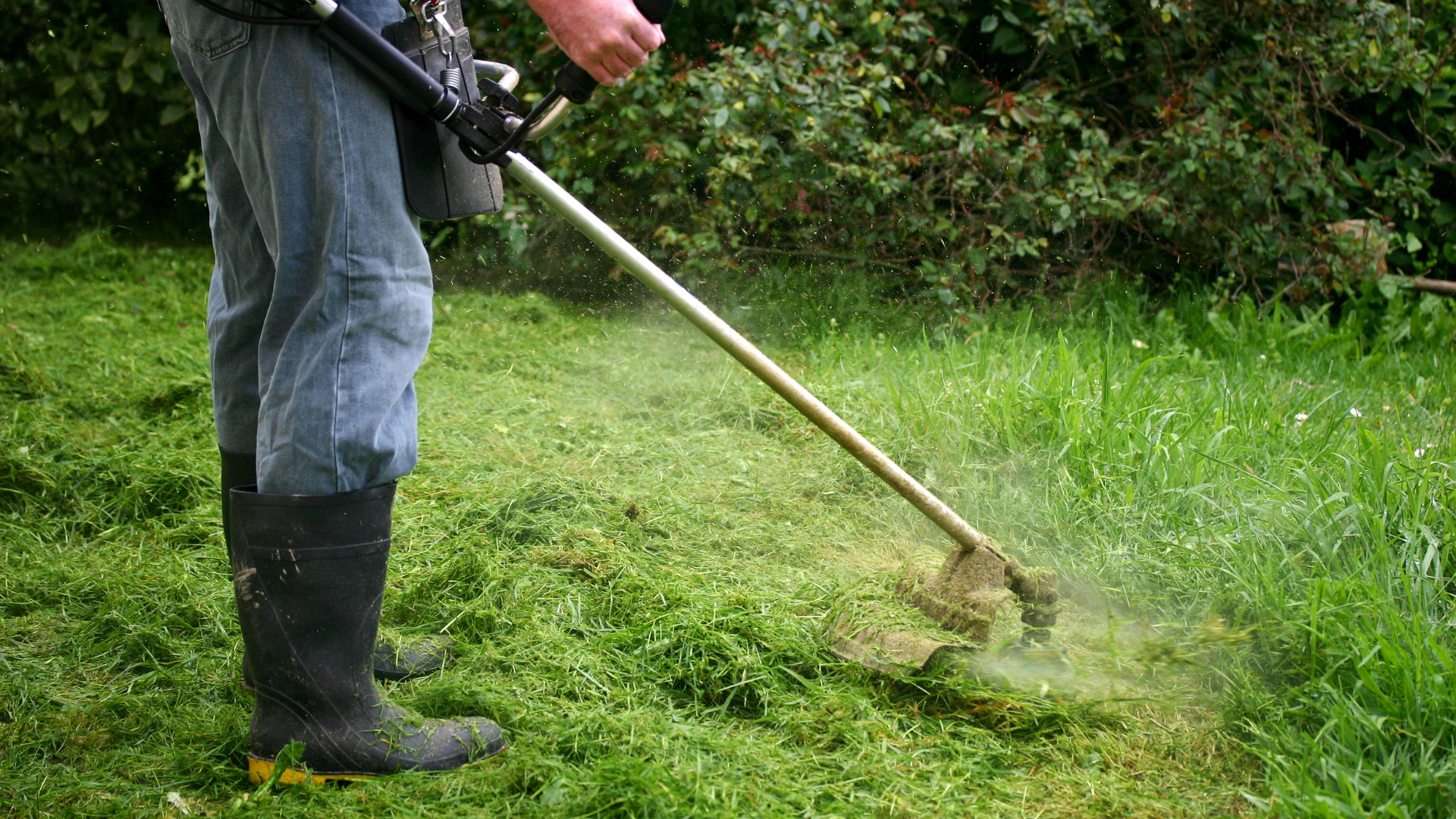 A man is mowing the grass with a lawn mower.