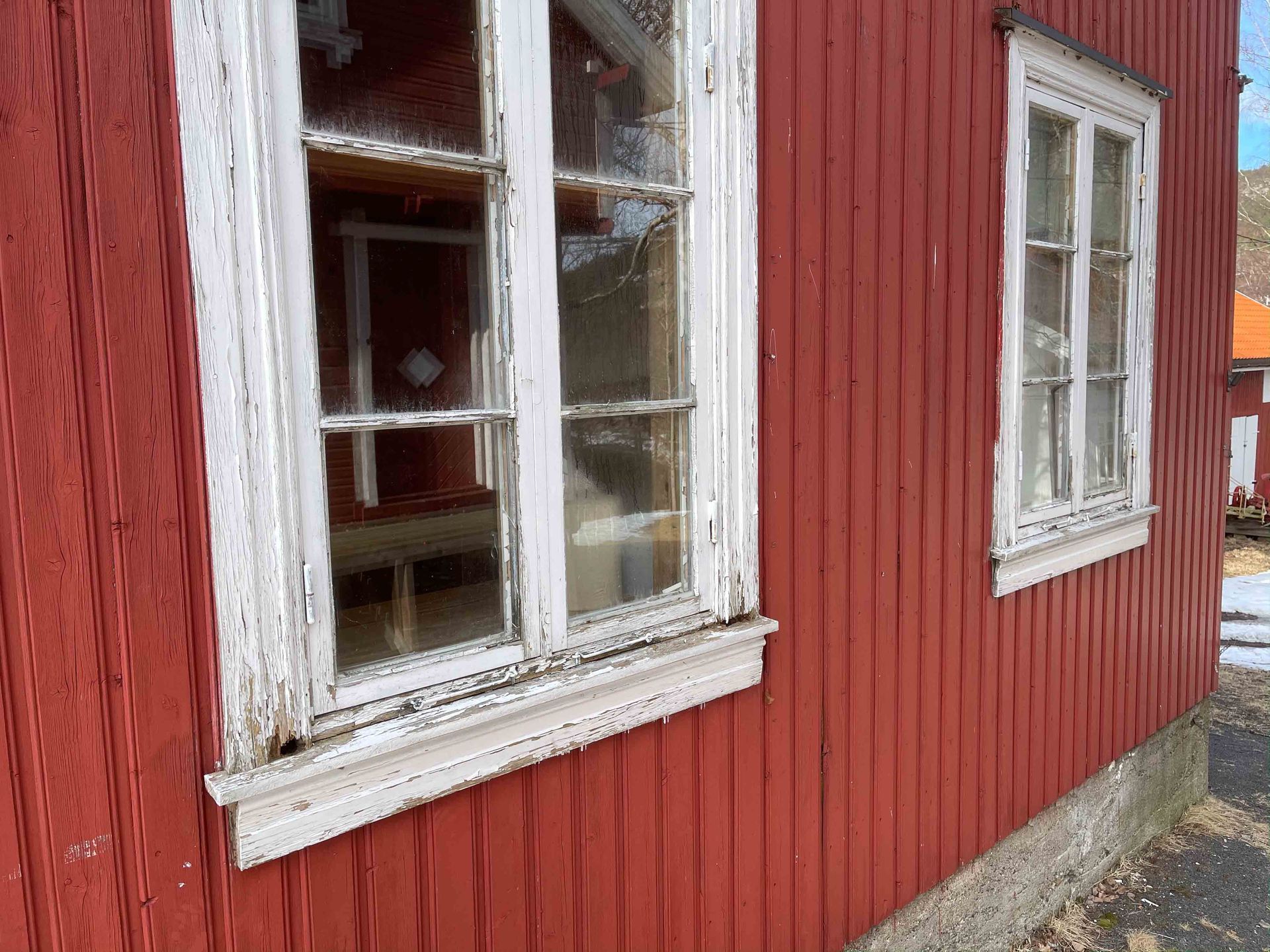 Rød trebygning med to hvitrammede vinduer; utvendig bilde.
