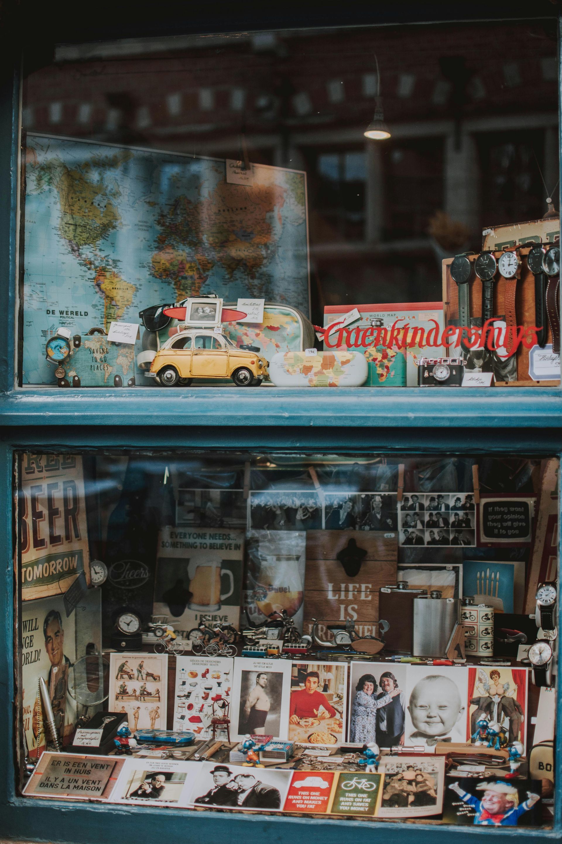 Shop window display with vintage items, including a toy car, maps, and photographs.