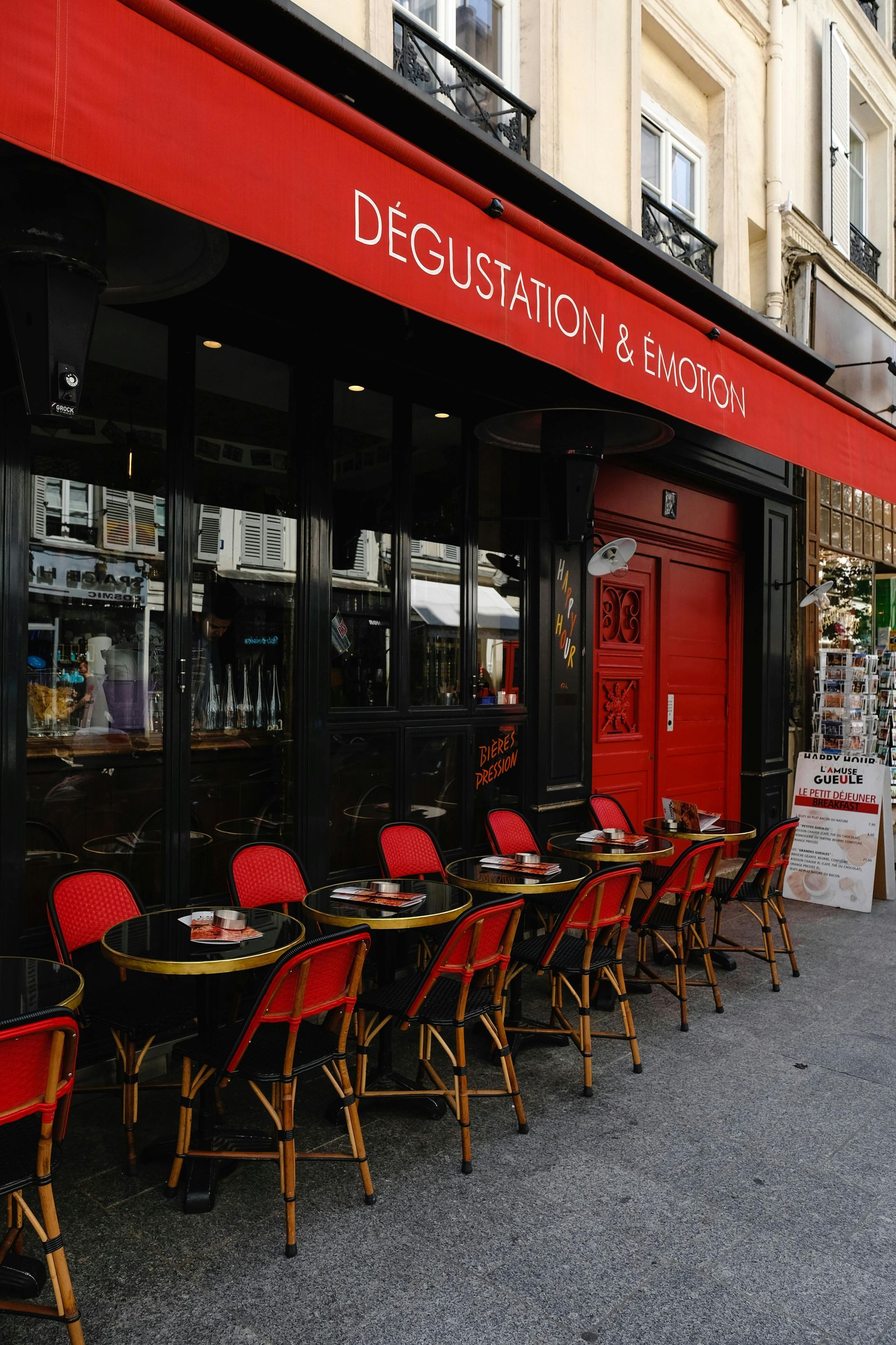 A Parisian cafe with red awning and chairs.